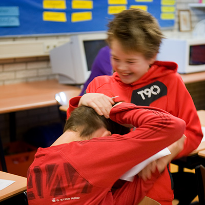 Twee jongens vliegen elkaar vriendschappelijk in de haren in de klas