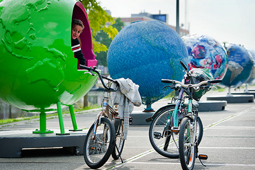 Een kind zit in een grote wereldbol tijdens de Coolglobes expositie