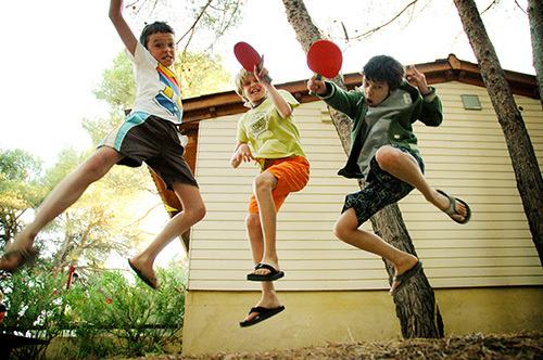 Springfoto van drie jongens met pingpongbatjes